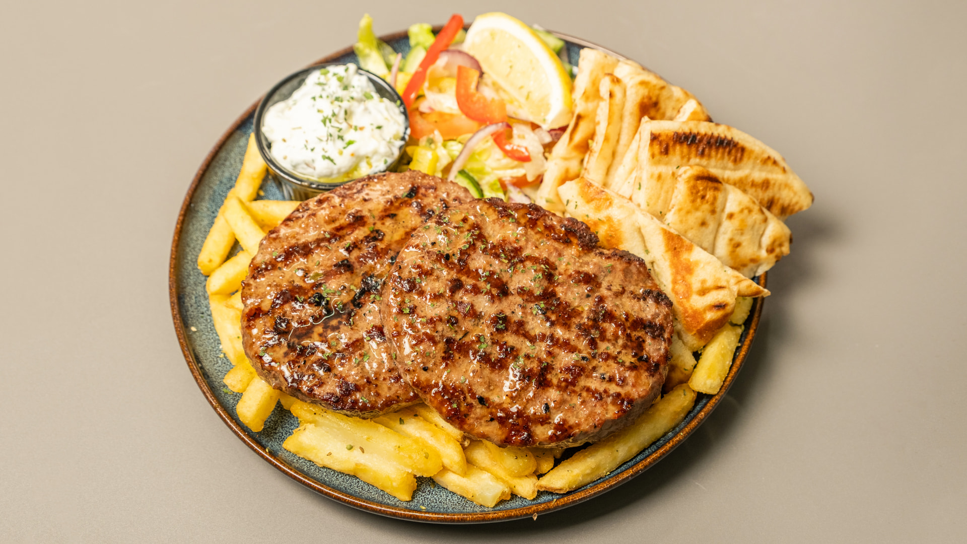 Grilled bifteki portion with chips, salad and pita